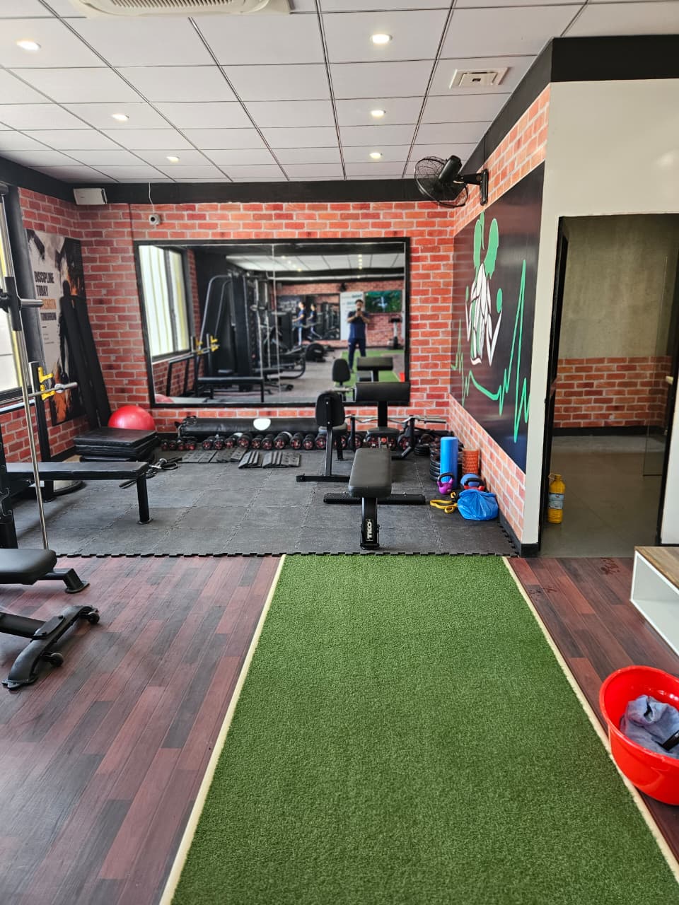 Free weight area with dumbbell rack, benches and mirrors at Core Fitness Lahore
